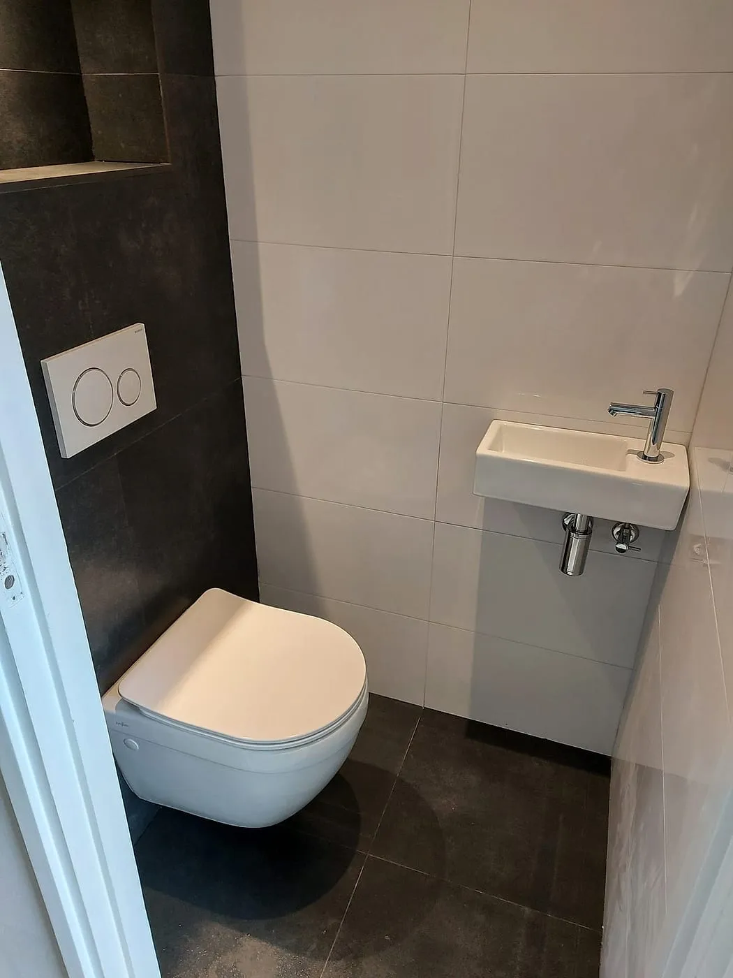 Hangtoilet met antracieten tegels en witte fontein na de renovatie — toiletrenovatie in De Hunze door BontBouw