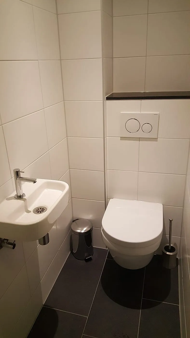 Hangtoilet met fontein en witte bedieningsplaat na de renovatie — toiletrenovatie in Beijum door BontBouw