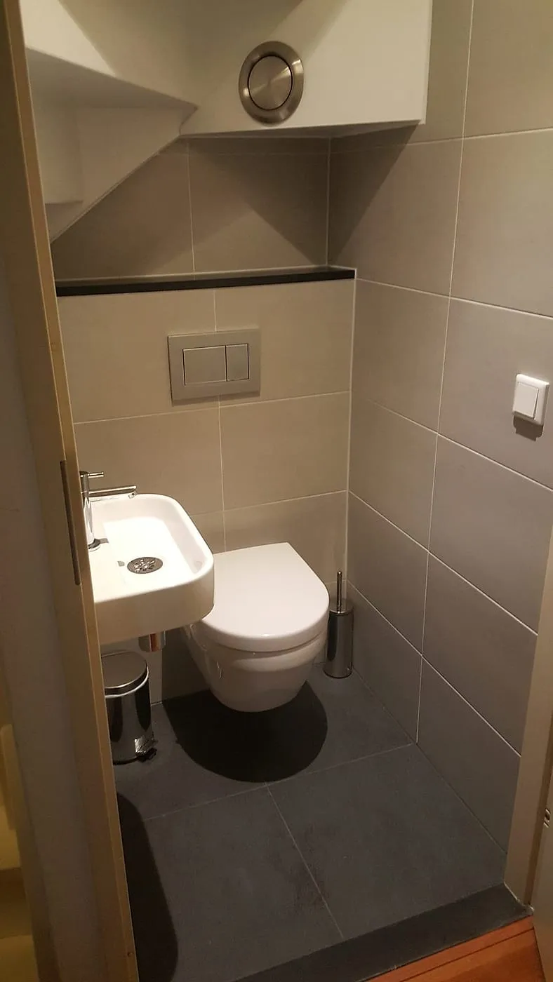 Hangtoilet met fontein onder de schuine trapkast na de renovatie — toiletrenovatie in De Hunze door BontBouw