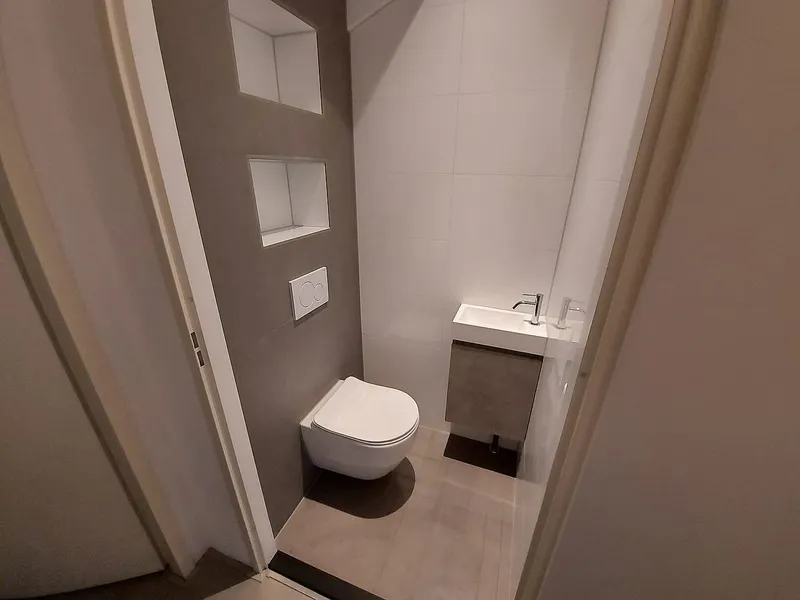 Hangtoilet met twee nissen en fonteinkastje in betonlook — toiletrenovatie in Schildersbuurt door BontBouw