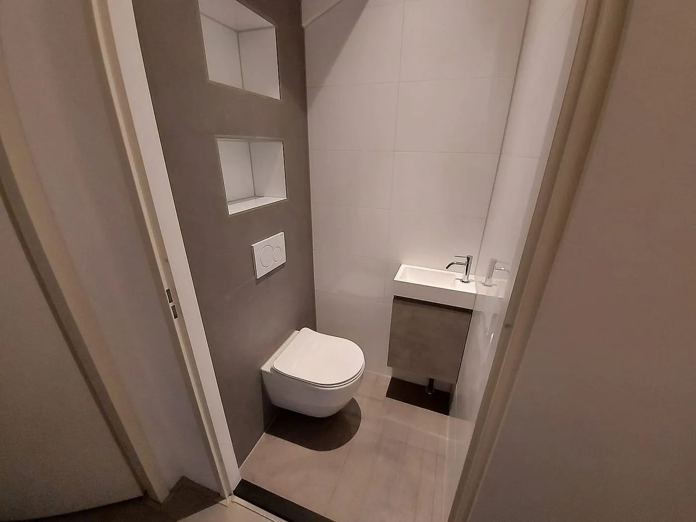 Hangtoilet met twee nissen en fonteinkastje in betonlook na de renovatie — toiletrenovatie in Schildersbuurt door BontBouw