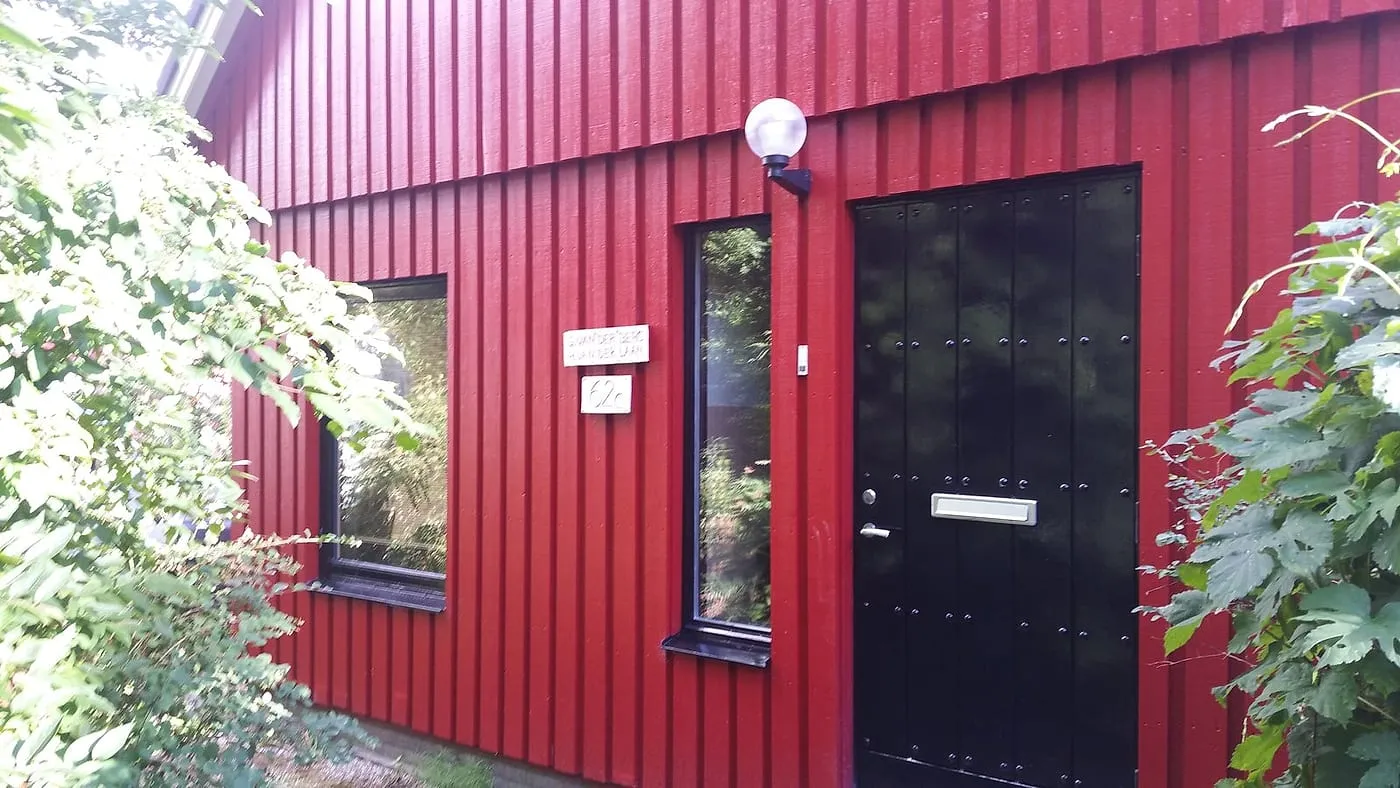 Zwarte voordeur met bolarmatuur in de geschilderde rode gevel na het werk — schilderwerk in Beijum door BontBouw