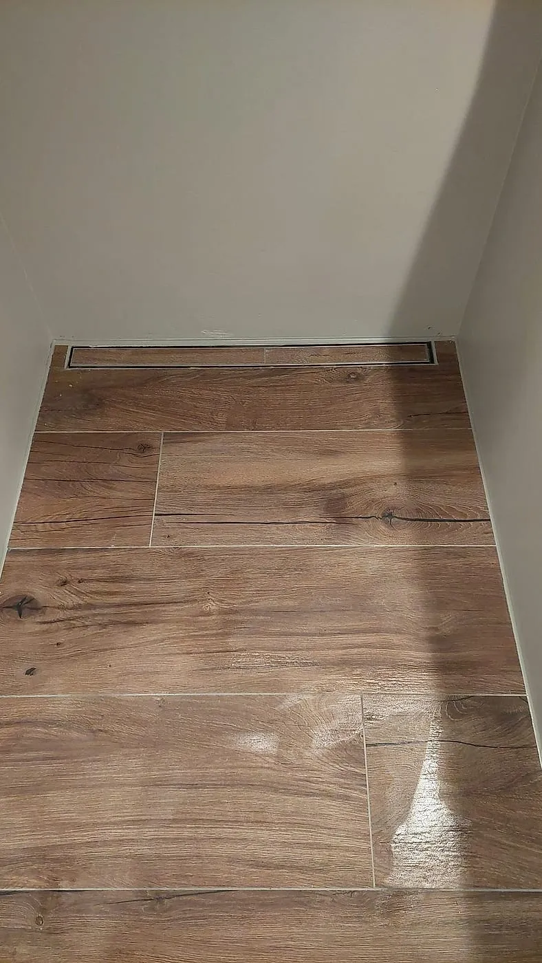 Houtlook vloertegels met rvs douchegoot tegen de wand — badkamerrenovatie in Beijum door BontBouw