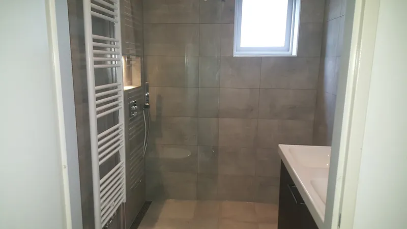 Inloopdouche met glazen wand onder het raam — badkamerrenovatie in De Hunze door BontBouw