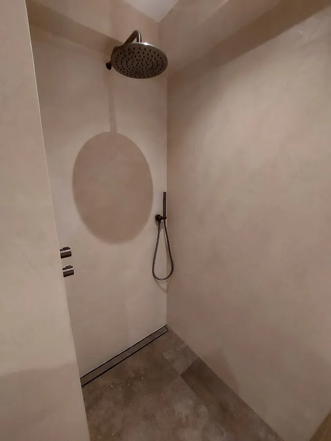 Inloopdouche met regendouche en wanden in beton cire — badkamerrenovatie in Groningen door BontBouw
