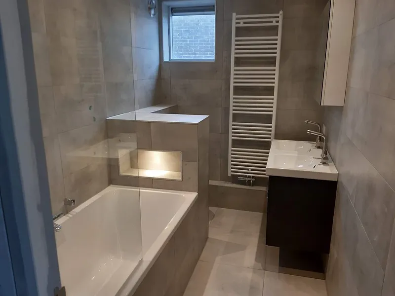 Ligbad met verlichte nis in tegelwand — badkamerrenovatie in De Hunze door BontBouw