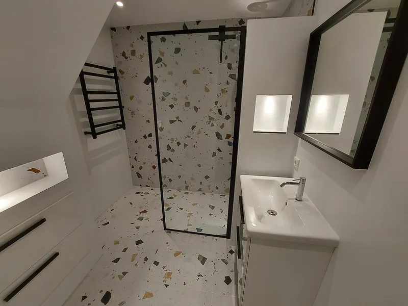 Terrazzotegels met zwart omlijnde douchewand — badkamerrenovatie in Schildersbuurt door BontBouw