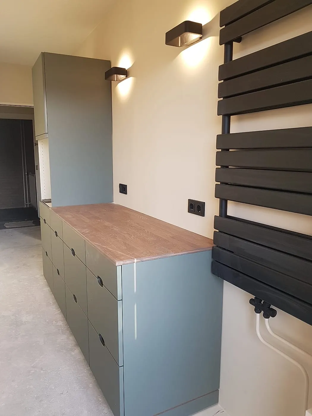 Groengrijze kastenwand met eiken blad en handdoekradiator na de renovatie — keukenrenovatie in Apeldoorn door BontBouw