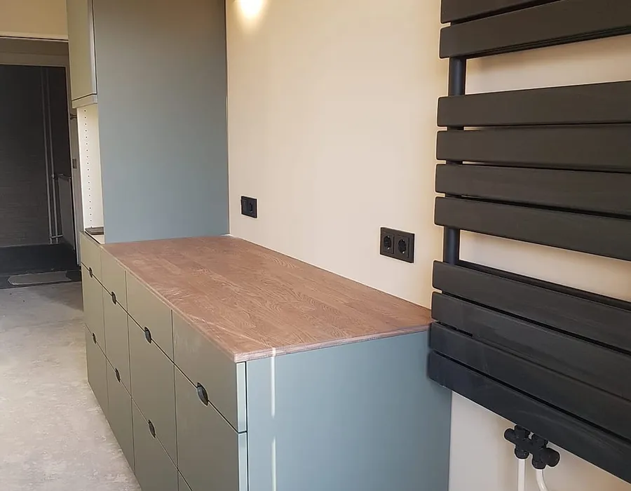 Verbouwde keuken in Groningen met een groengrijze kastenwand, eiken werkblad en zwarte handdoekradiator