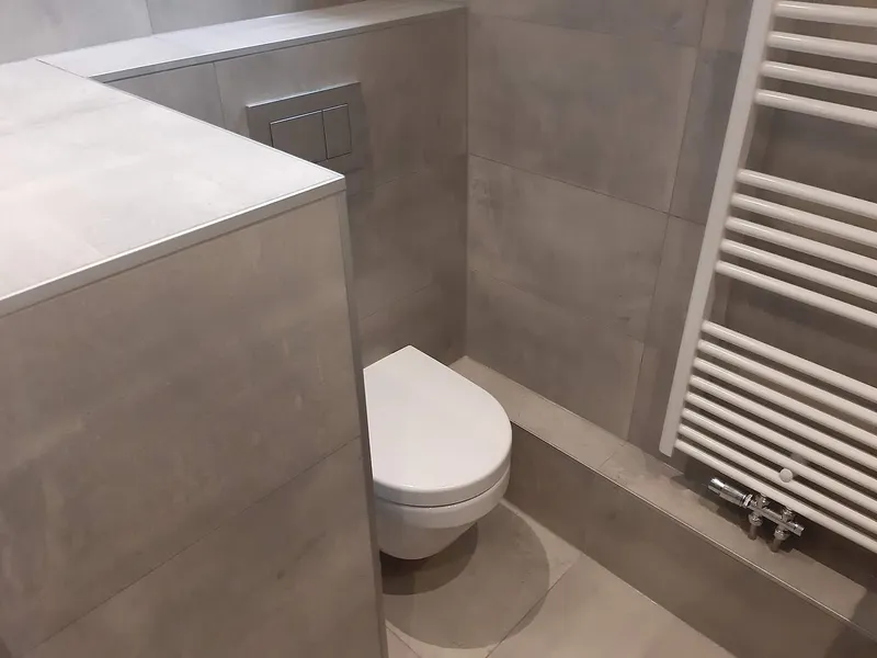 Hangend toilet achter halfhoge tegelwand — badkamerrenovatie in De Hunze door BontBouw