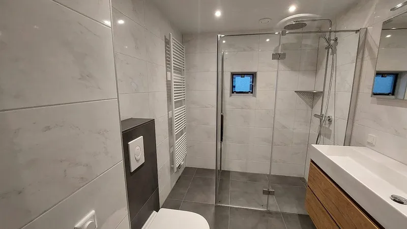 Hangtoilet met antracieten inbouwkast en witte handdoekradiator — badkamerrenovatie in De Hunze door BontBouw