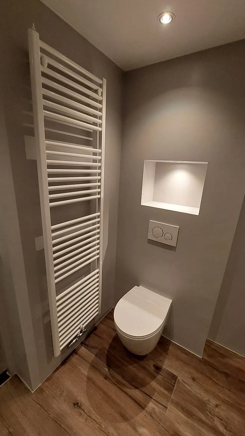 Hangtoilet met verlichte nis en witte handdoekradiator — badkamerrenovatie in Beijum door BontBouw