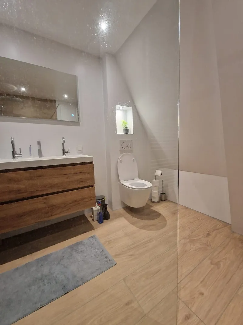 Hangtoilet onder de schuine wand met houtlook vloertegels — badkamerrenovatie in Leeuwarden door BontBouw