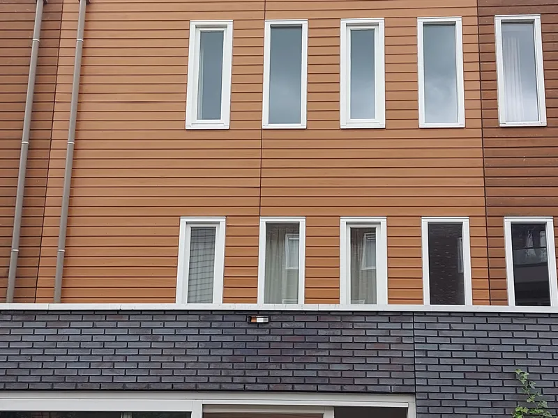 Houten gevelbekleding met witte kozijnen boven donkere baksteen — schilderwerk in Groningen door BontBouw