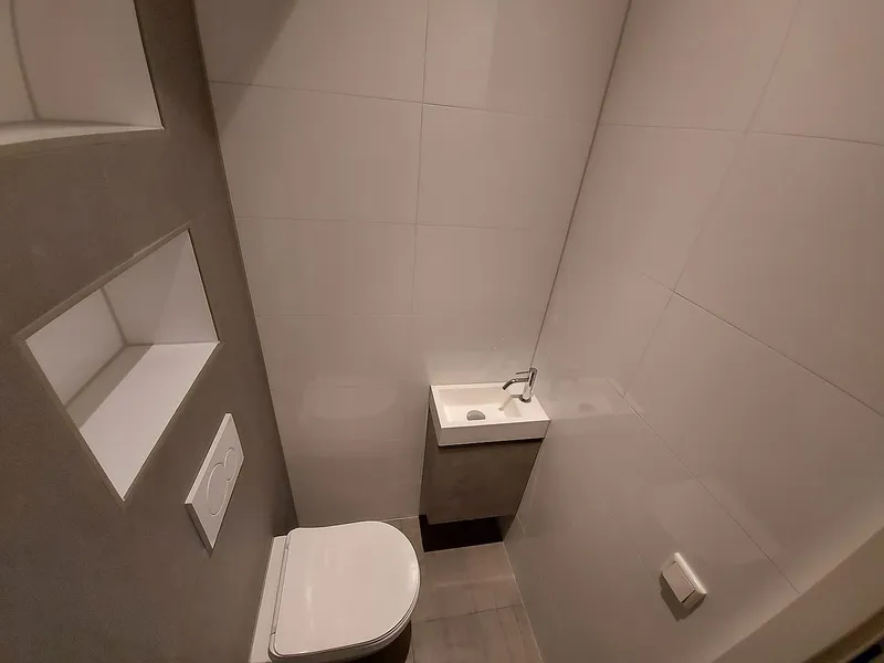 Nissen in de taupe tegelwand met fonteinkastje — toiletrenovatie in Schildersbuurt door BontBouw