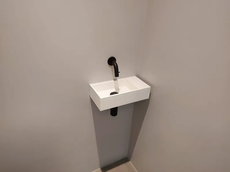 Smalle fontein met zwarte wandkraan en zwarte sifon — toiletrenovatie in Korrewegwijk door BontBouw
