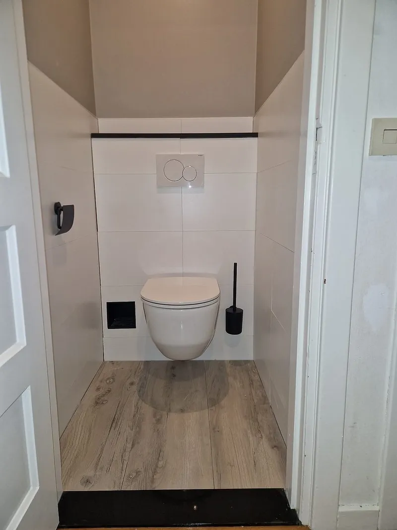 Witte tegelwand met zwarte afdeklijst — toiletrenovatie in Korrewegwijk door BontBouw