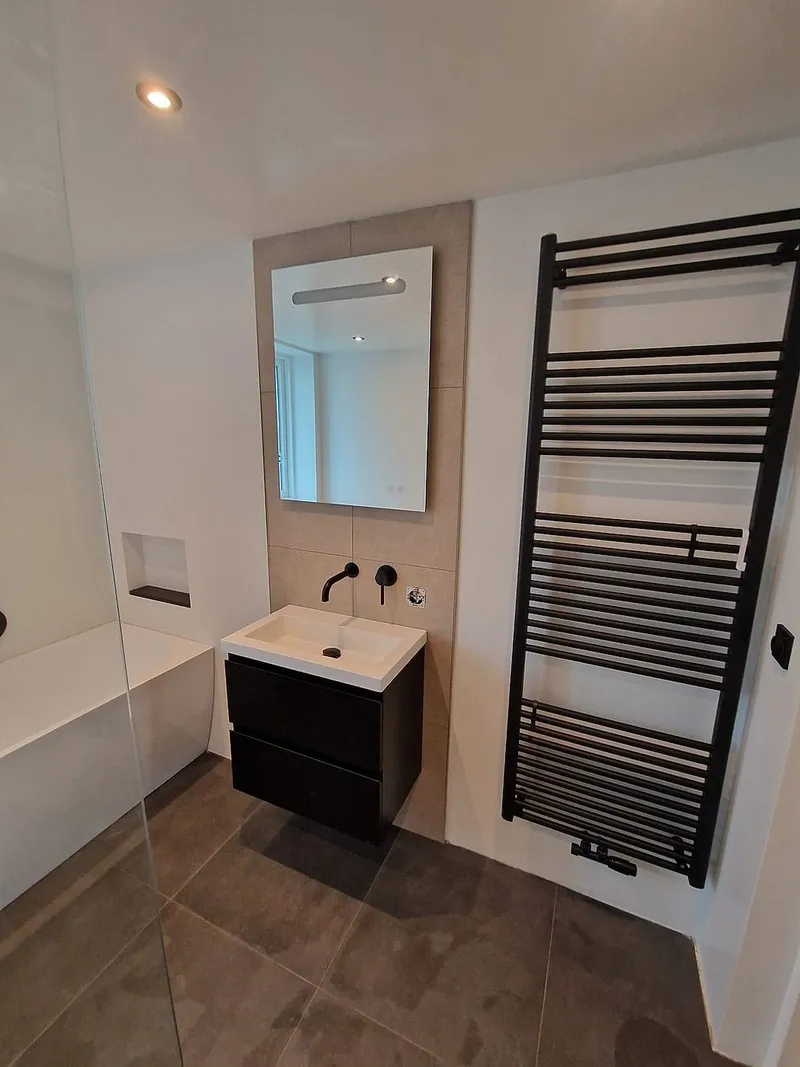 Zwart wastafelmeubel met handdoekradiator — badkamerrenovatie in Ulgersmaborg door BontBouw
