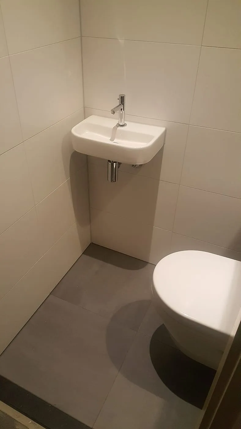 Fontein met chromen kraan naast het hangtoilet — toiletrenovatie in De Hunze door BontBouw