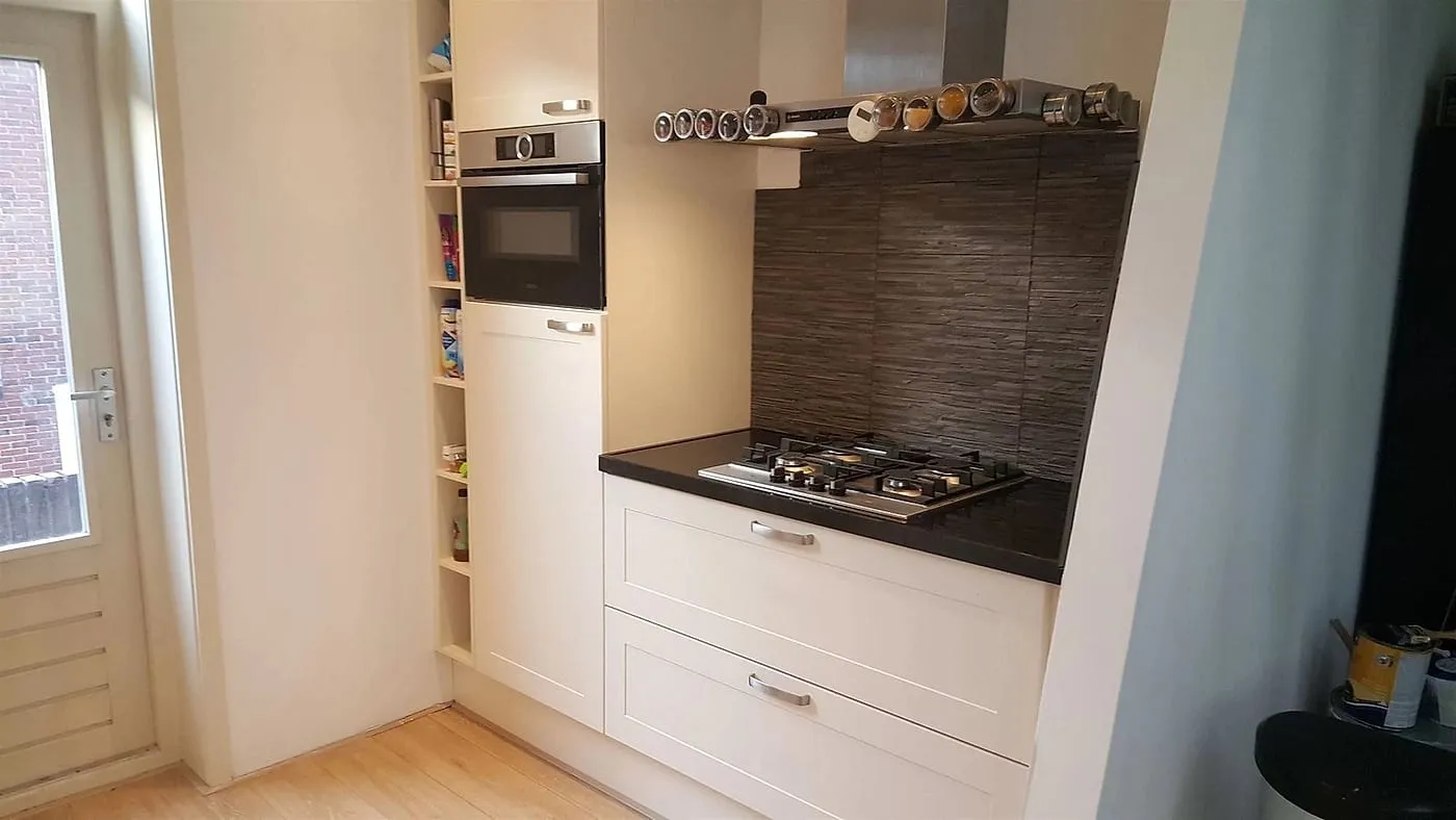 Creme keuken met natuursteen achterwand na de renovatie — keukenrenovatie in Helpman door BontBouw