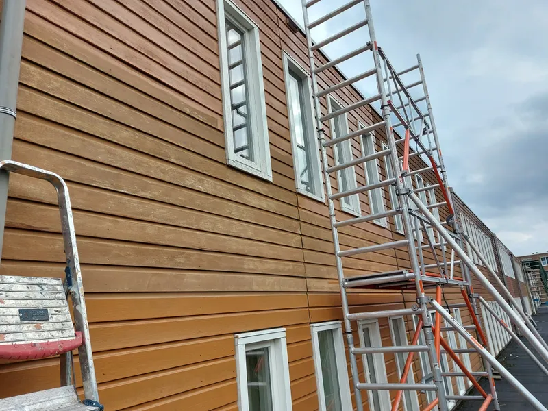 Gevelbekleding half behandeld met rolsteiger langs de gevel — schilderwerk in Groningen door BontBouw