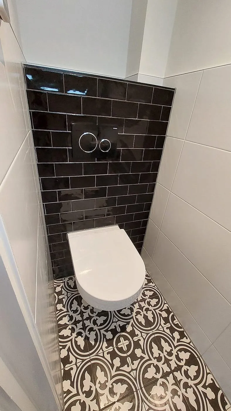 Hangtoilet tegen zwarte metrotegels met patroonvloer — toiletrenovatie in Korrewegwijk door BontBouw