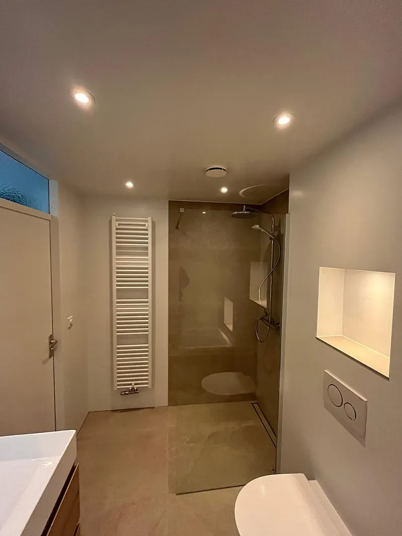 Inloopdouche met glazen wand en witte handdoekradiator — badkamerrenovatie in Beijum door BontBouw