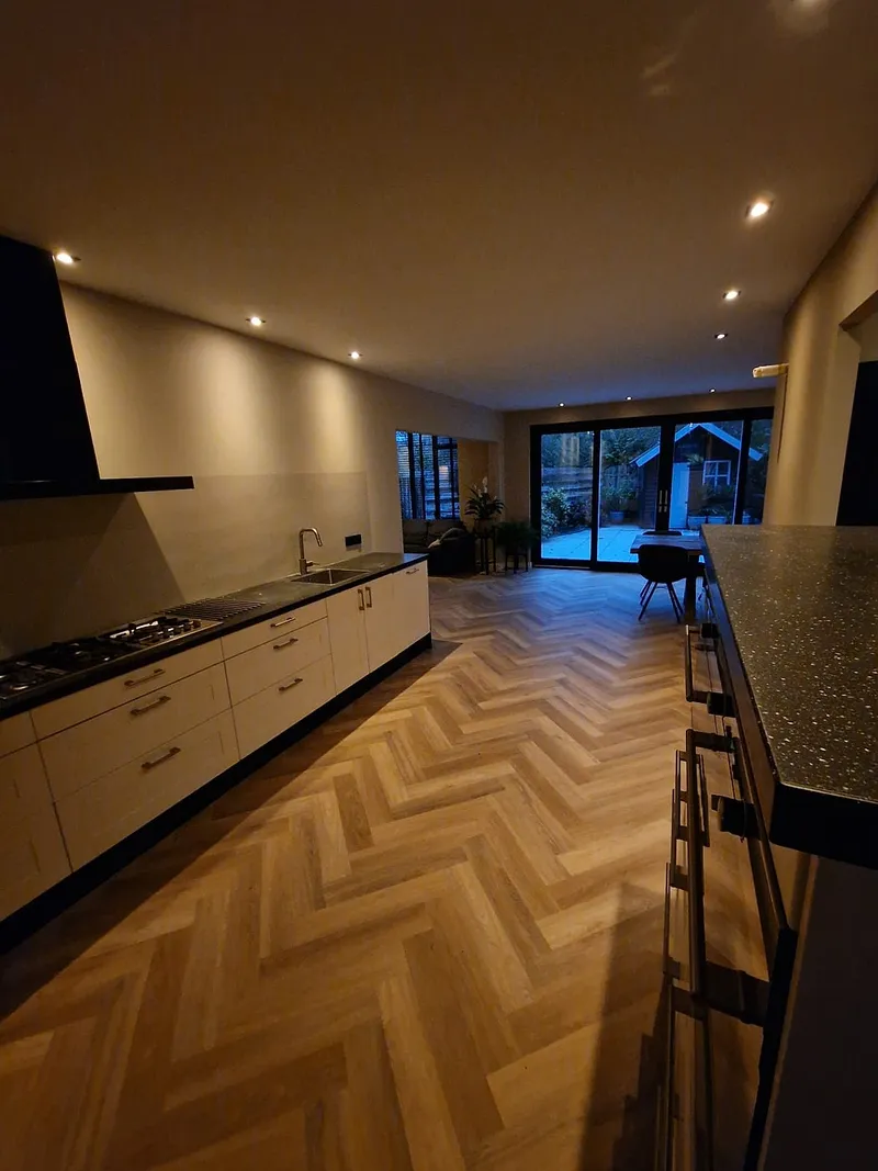 Keuken met kookeiland en zicht op de tuin — complete verbouwing in Beijum door BontBouw