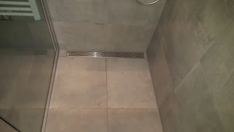 Lange rvs douchegoot langs de wand — badkamerrenovatie in De Hunze door BontBouw