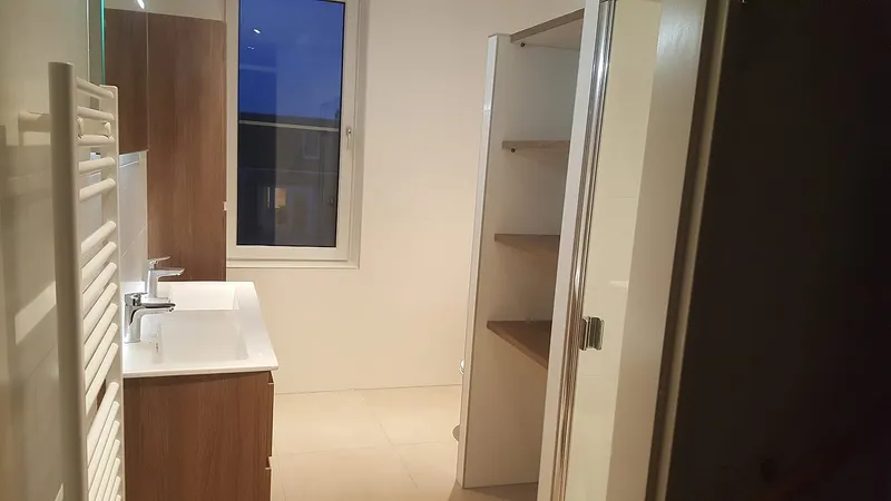 Handdoekradiator naast het wastafelmeubel bij het raam — badkamerrenovatie in Hoogezand door BontBouw