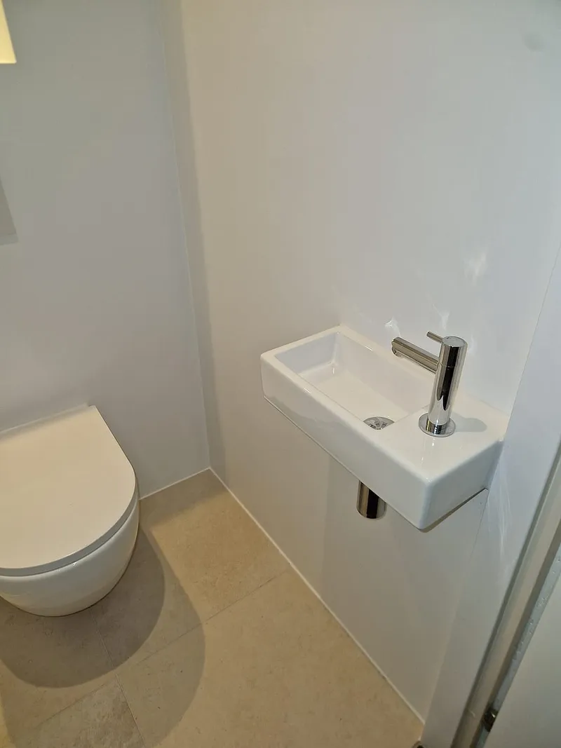 Smalle fontein met chromen kraan naast het hangtoilet — toiletrenovatie in Ulgersmaborg door BontBouw