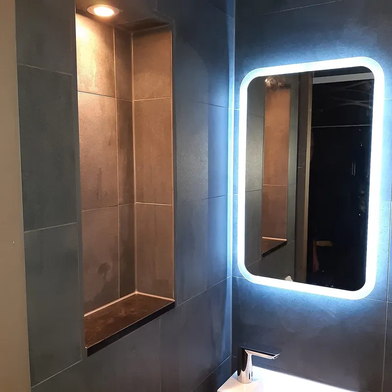 Verlichte nis met lichte tegels naast de led spiegel — toiletrenovatie in Beijum door BontBouw