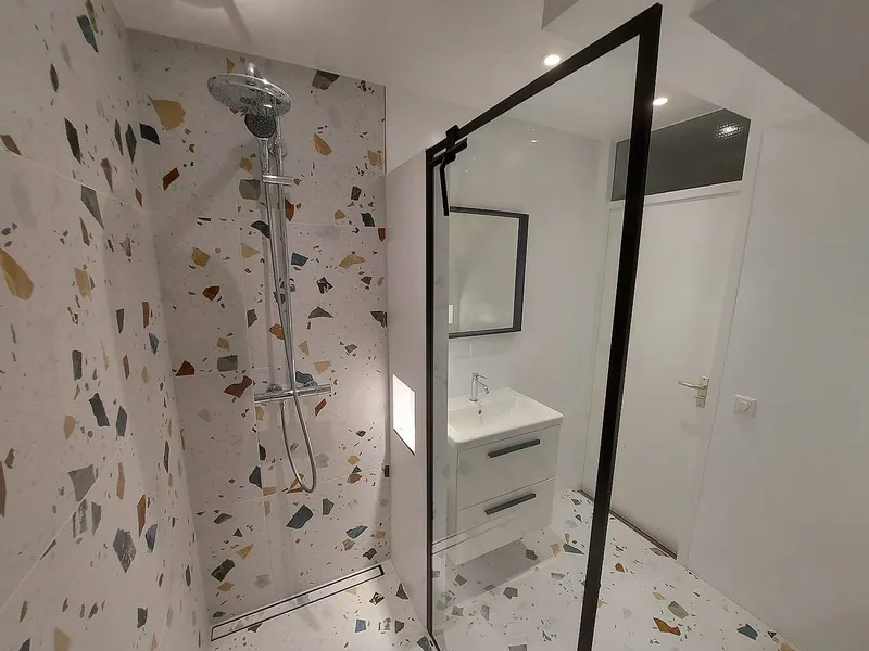 Chromen regendouche tegen terrazzotegels — badkamerrenovatie in Schildersbuurt door BontBouw