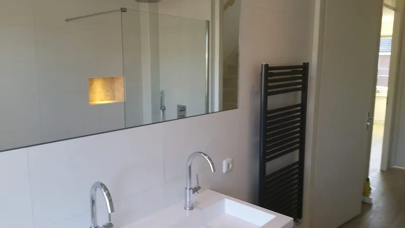 Dubbele wastafel met chromen kranen en antracieten handdoekradiator — badkamerrenovatie in Haren door BontBouw