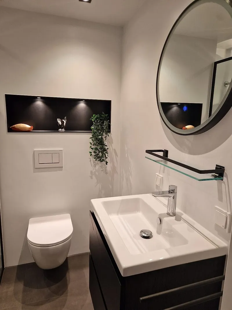 Hangtoilet met zwarte verlichte nis en antracieten wastafelmeubel — badkamerrenovatie in De Hunze door BontBouw