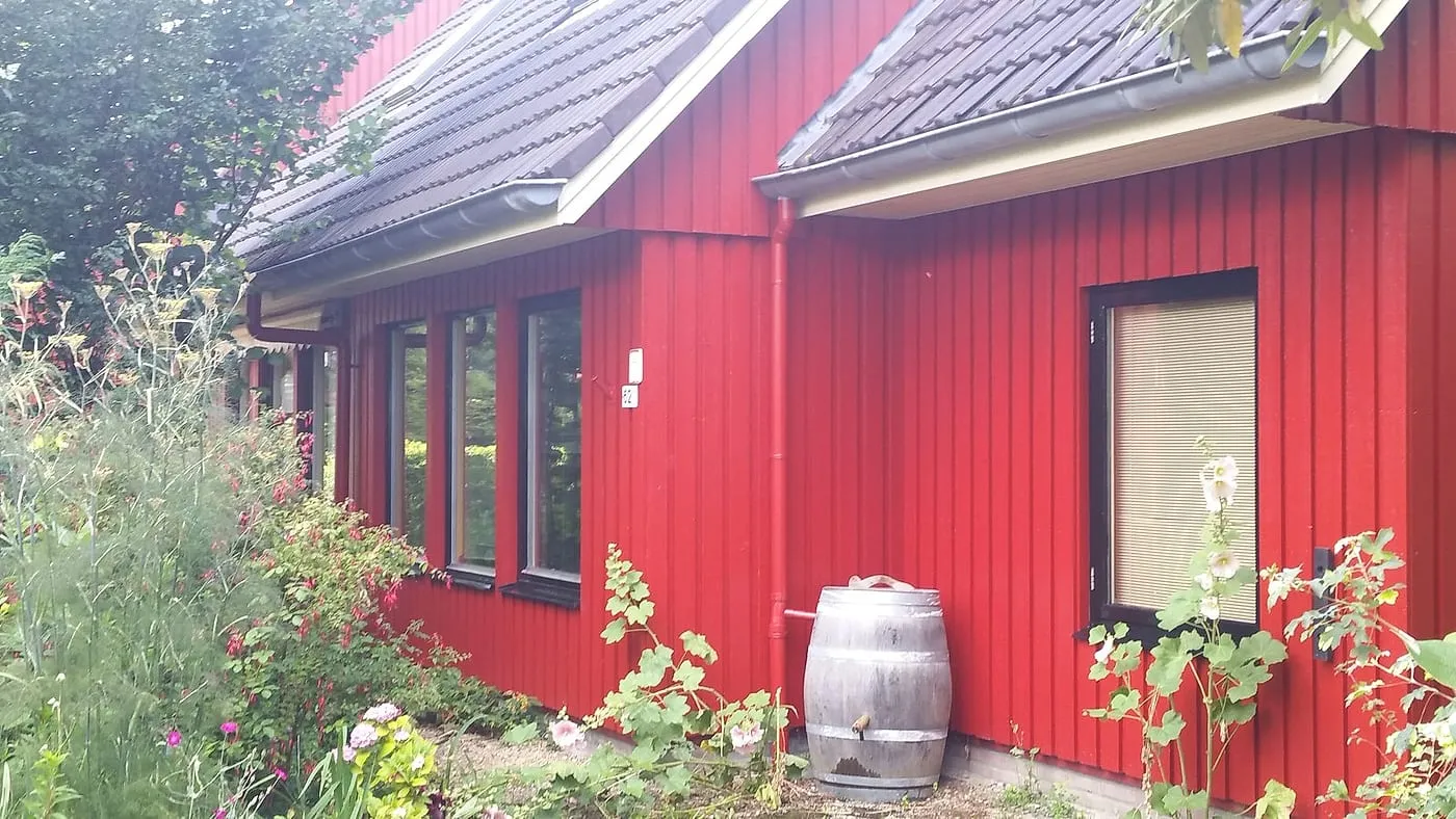 Geschilderde rode gevel met zwarte kozijnen en regenton na het werk — schilderwerk in Beijum door BontBouw