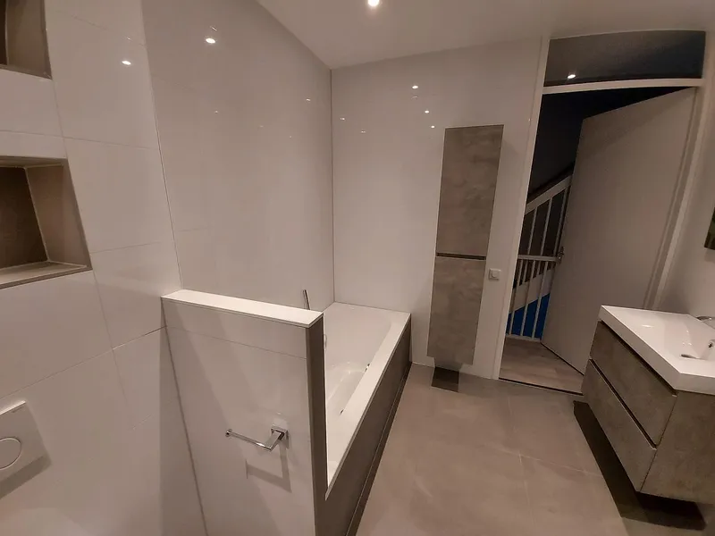 Ligbad met betonlook badpaneel — badkamerrenovatie in Schildersbuurt door BontBouw