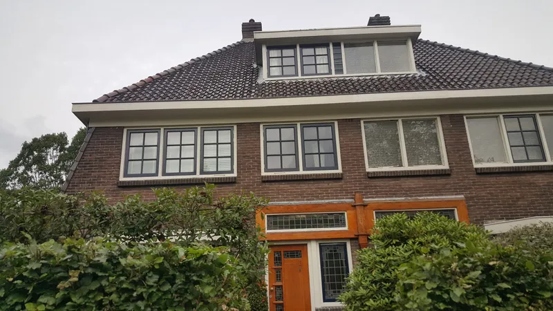 Voorgevel met creme kozijnen en donkere ramen met roedes — schilderwerk in Assen door BontBouw