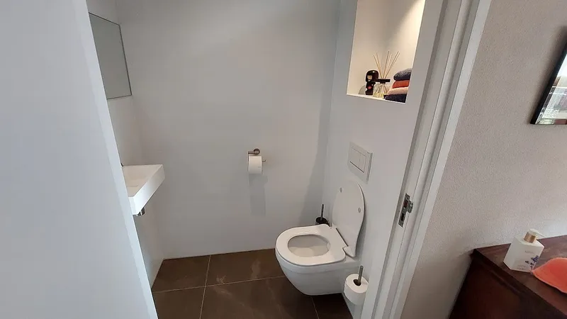 Hangtoilet met verlichte nis en smalle fontein — badkamerrenovatie in Eelderwolde door BontBouw