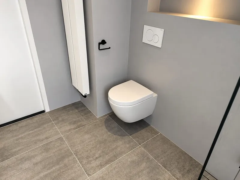 Hangtoilet met witte designradiator — badkamerrenovatie in Korrewegwijk door BontBouw