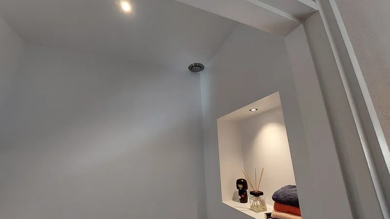 Verlichte nis met handdoeken in de witte toiletwand — badkamerrenovatie in Eelderwolde door BontBouw