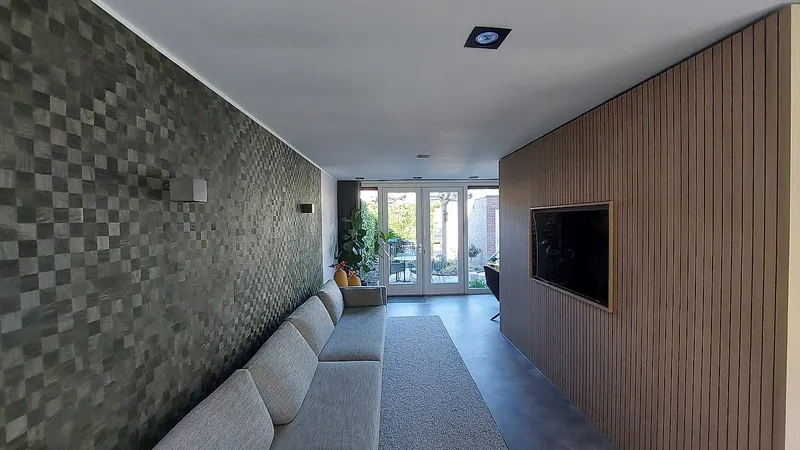Houten lattenwand met televisie tegenover de mozaiekwand — complete verbouwing in Eelderwolde door BontBouw