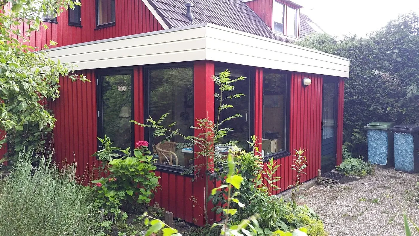 Strak geschilderde rode houtgevel met witte dakrand na het werk — schilderwerk in Beijum door BontBouw