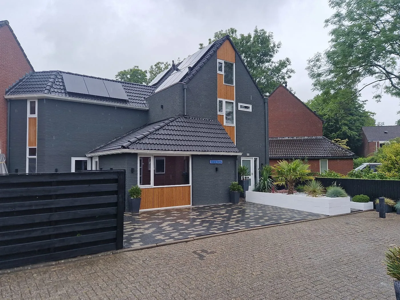 Antracietgrijze gevel met houten delen en nieuwe bestrating na de verbouwing — complete verbouwing in Beijum door BontBouw