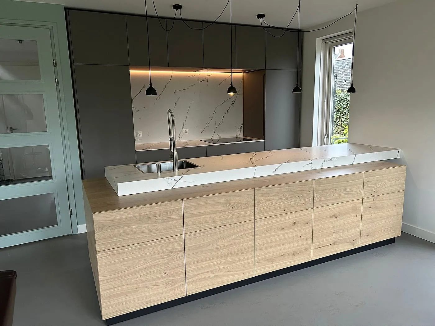 Eiken kookeiland met blad in marmerlook en donkere kastenwand na de renovatie — keukenrenovatie in Zuidlaren door BontBouw
