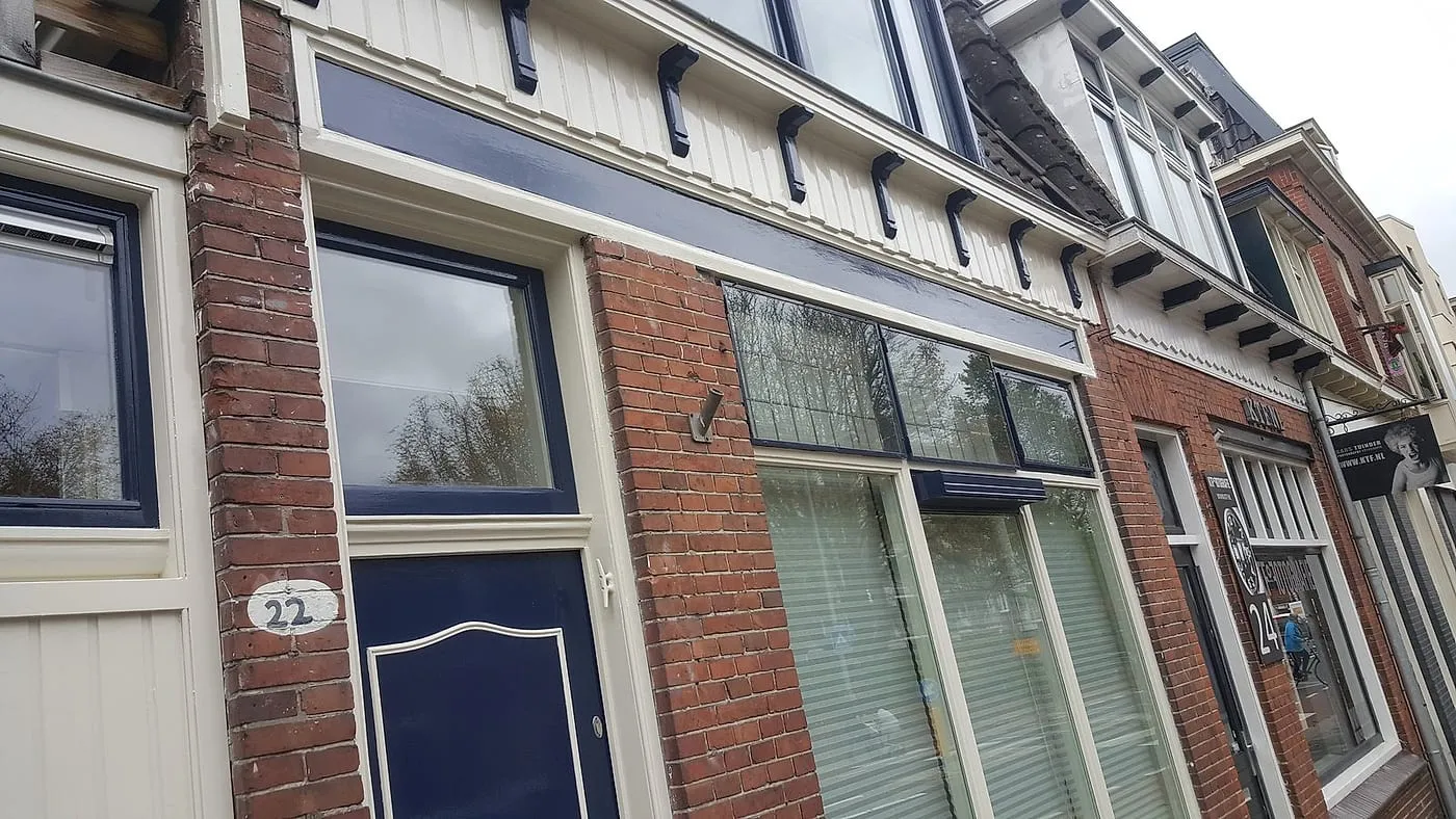 Geschilderde houten kroonlijst met donkerblauwe kozijnen na het werk — schilderwerk in Eeldersingel door BontBouw