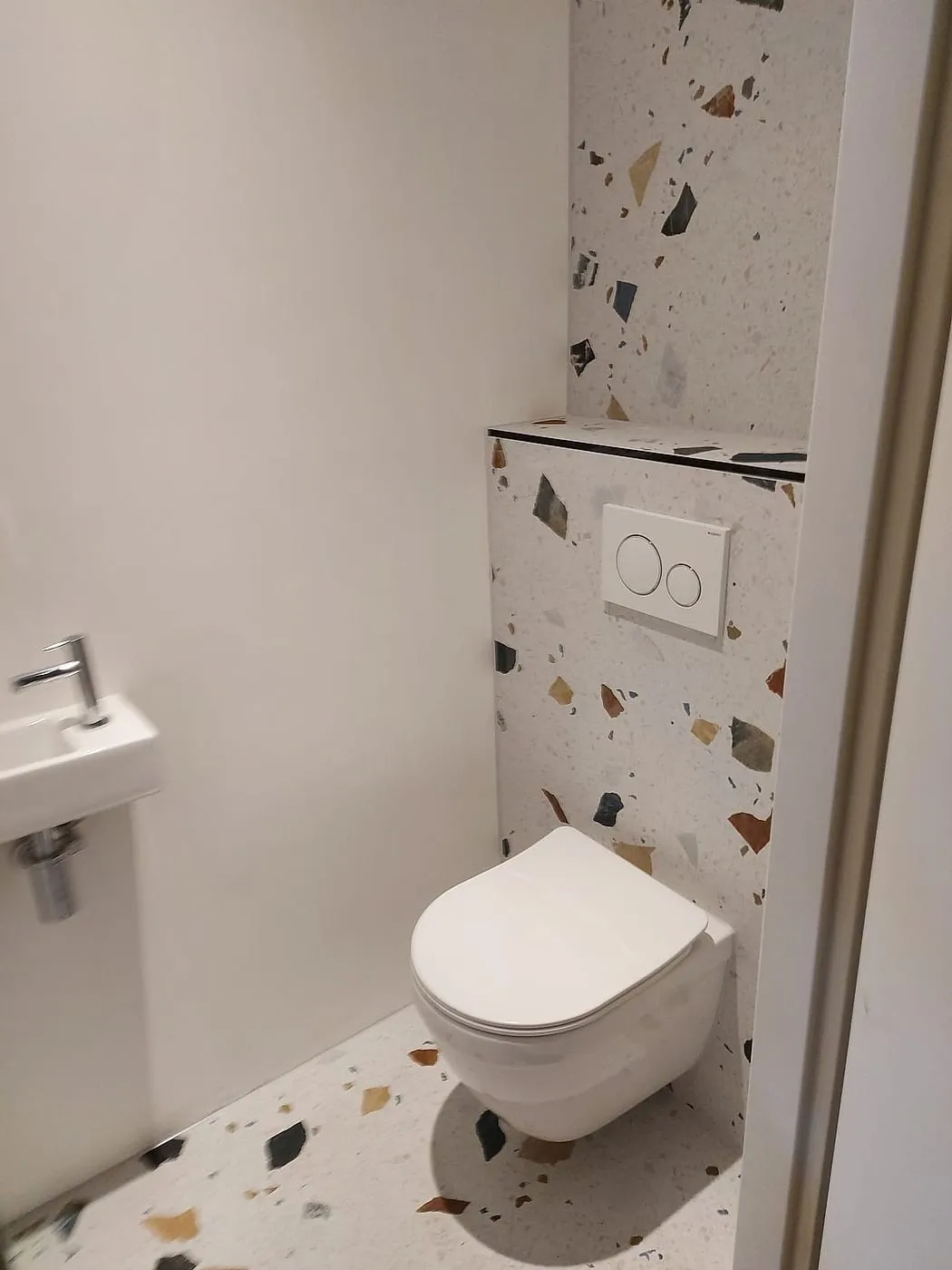 Terrazzo achterwand met hangtoilet na de renovatie — toiletrenovatie in Schildersbuurt door BontBouw