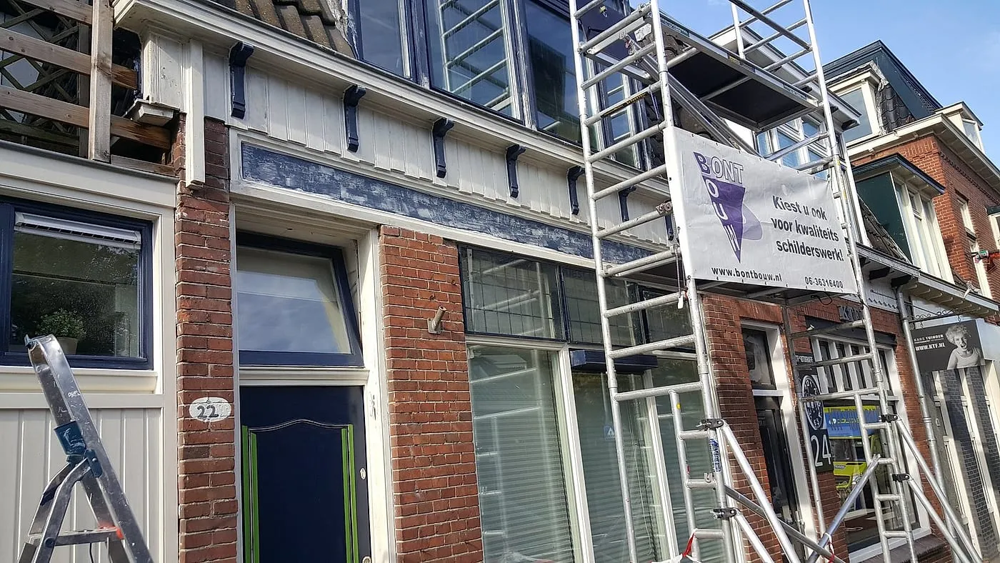Afgebladderde houten kroonlijst met rolsteiger langs de gevel vóór het werk — schilderwerk in Eeldersingel door BontBouw