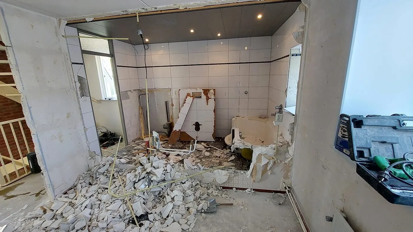 Gesloopte badkamer met oud ligbad en puin op de vloer vóór de renovatie — badkamerrenovatie in De Hunze door BontBouw