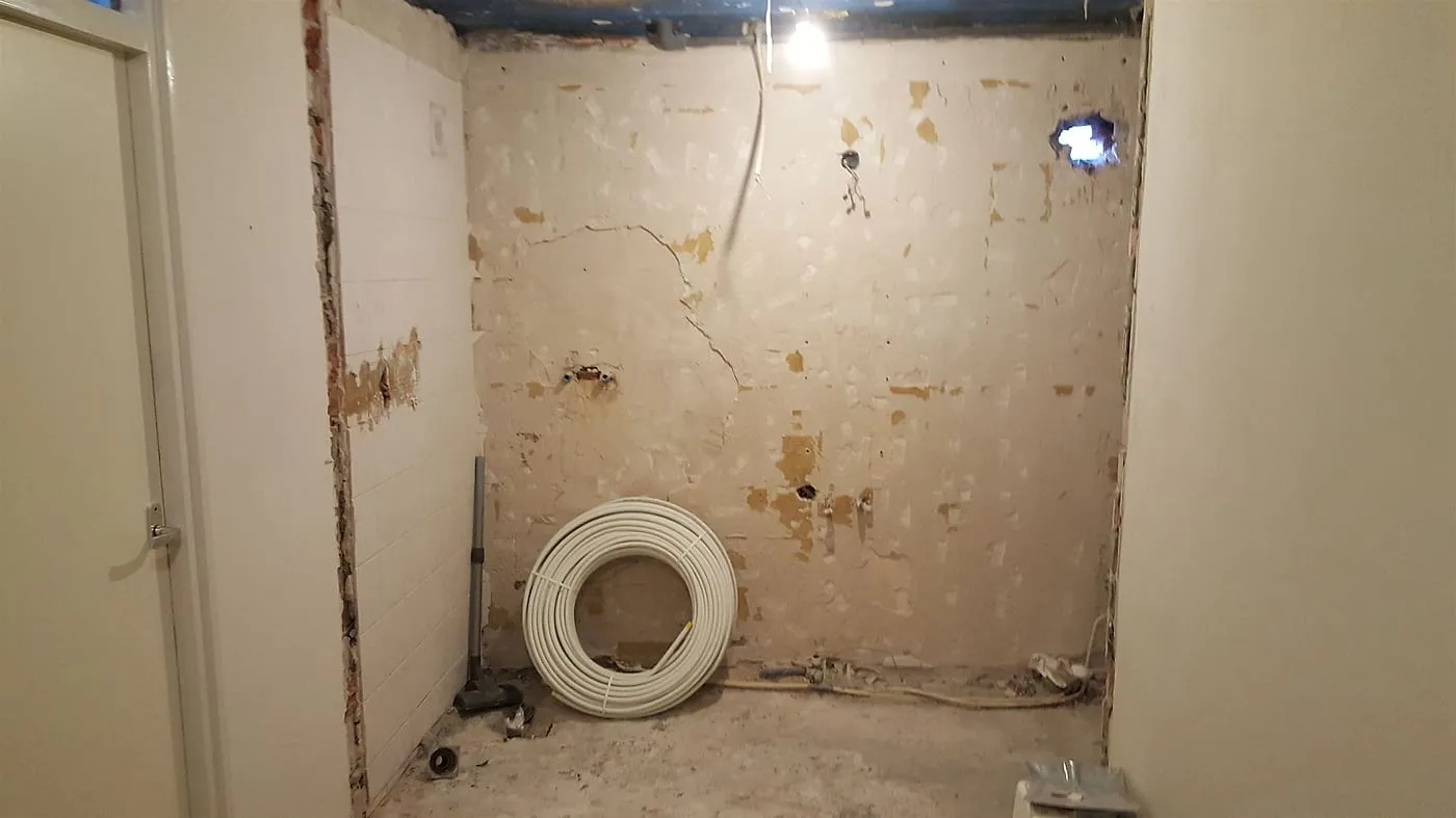 Gestripte badkamer met kale wanden en nieuw leidingwerk vóór de renovatie — badkamerrenovatie in Peize door BontBouw